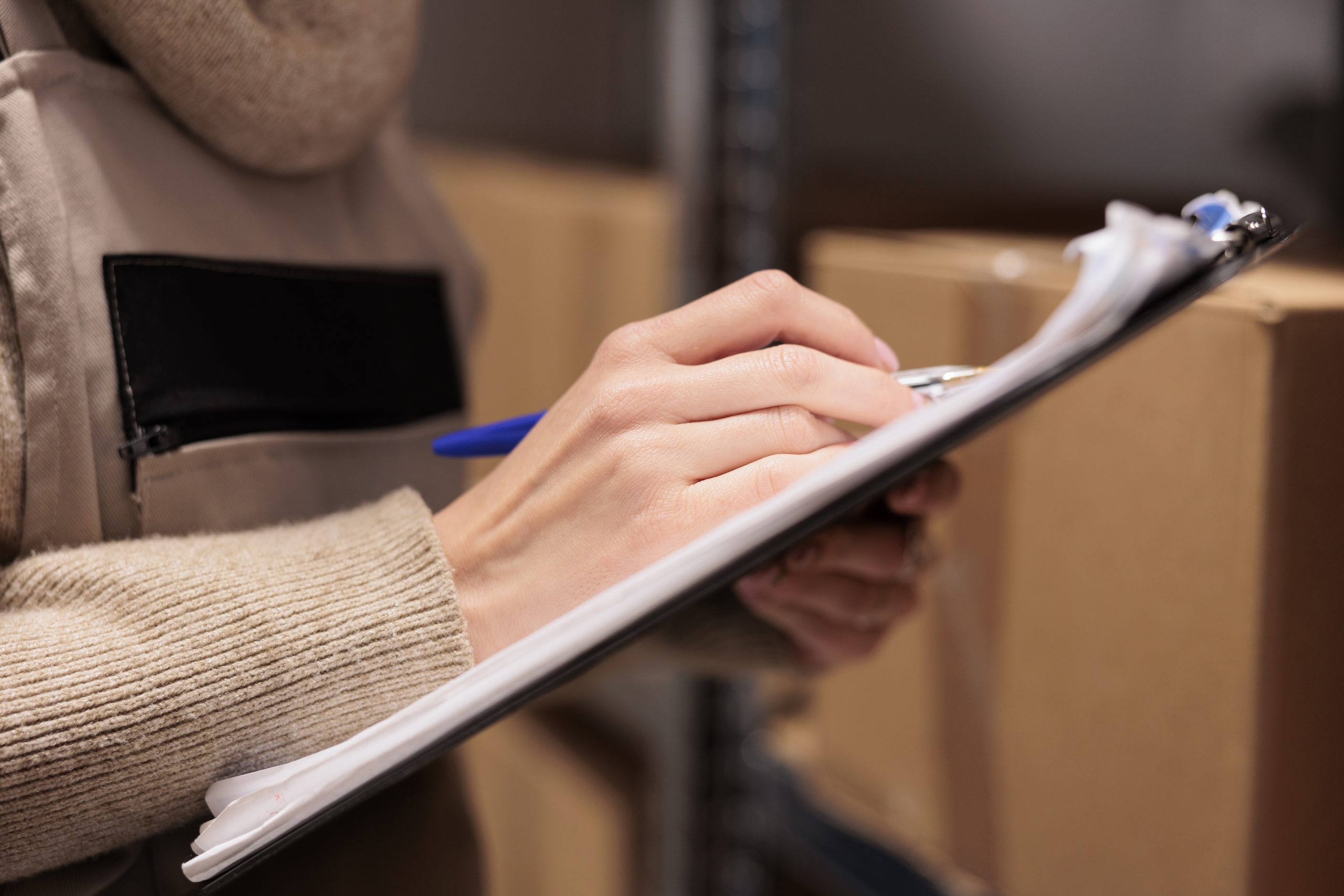 Postal office storage worker holding clipboard in warehouse